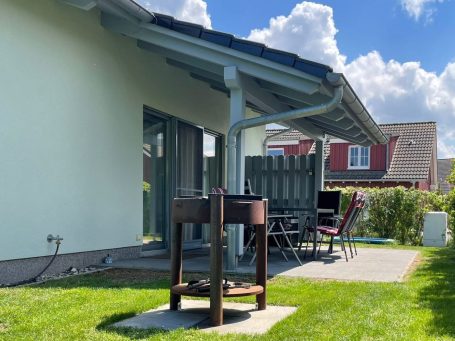 Ein modernes, helles Ferienhaus mit Garten und Satellitenschüssel.